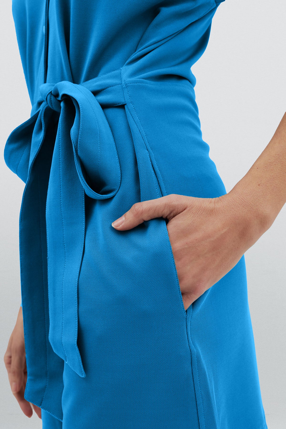 Mono corto de mujer color azul con detalle de cinturón y bolsillos laterales para mayor comodidad. Foto detalle